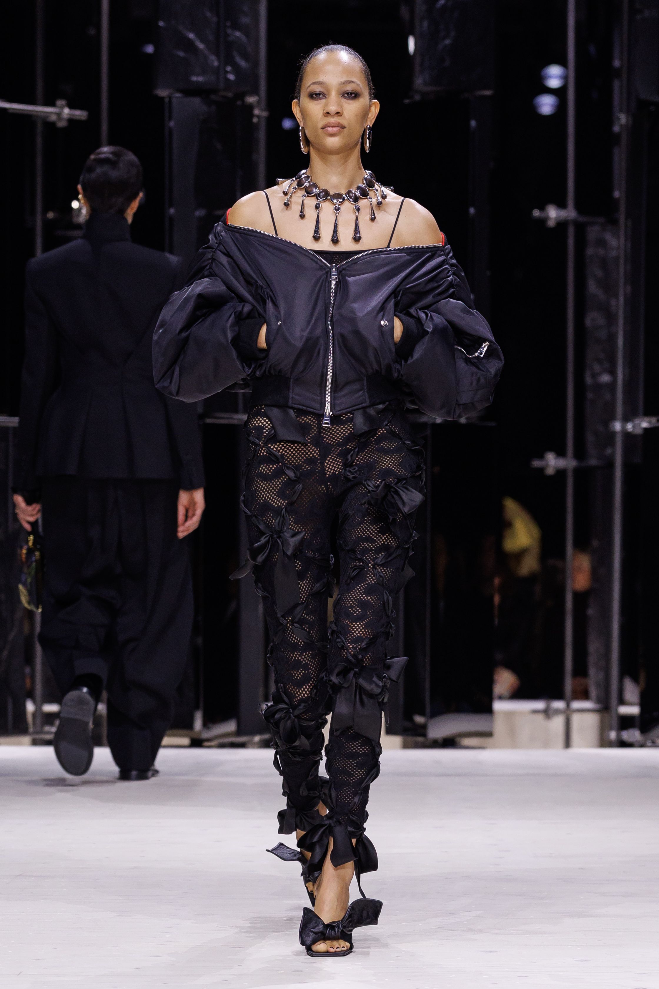 Givenchy 2026秋冬在现代建筑空间中呈现一场充满戏剧性的时装叙事：雕塑式西装、亮色斗篷、结构礼服与夸张装饰共同构建品牌标志性的高级时装气质。蓝色、红色与黄色的高饱和色彩与黑白经典形成鲜明对比，服装通过立体剪裁与夸张廓形展现出强烈视觉张力。整场系列在优雅与戏剧之间取得平衡，展现现代高级时装的力量-顽石频道趋势研究